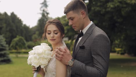 Newlyweds,-caucasian-groom-with-bride-walking,-embracing,-hugs-in-park,-wedding-couple