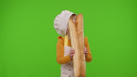 Child-girl-cook-chef-baker-in-apron-and-hat-sniffing-two-baguettes,-fooling-around,-dancing