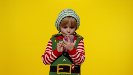 Kid-girl-Christmas-elf-Santa-helper-types-something-on-mobile-phone-enjoys-browsing-social-media