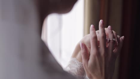 Bride-in-night-gown,-veil-with-engagement-ring-near-window.-Face-close-up-smiling.-Wedding-morning