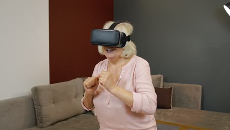 Happy-senior-woman-in-virtual-reality-headset-glasses,-trying-to-touch-something,-watching-3D-video