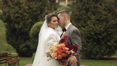 Newlyweds,-caucasian-groom-with-bride-walking,-embracing,-hugs-in-park,-wedding-couple