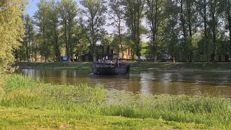 Großes-Holzboot-Voller-Menschen-Schwimmt-Auf-Dem-Fluss-Durch-Die-Stadt,-Tolle-Sommerstimmung