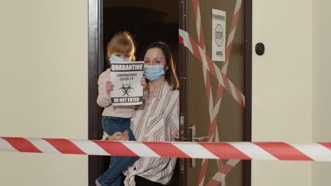 Sick-mother-with-kid-daughter-in-medical-masks-opening-home-door,-coronavirus-quarantine-lockdown