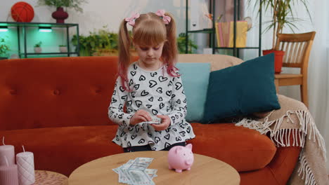 Niña-Pequeña-Poniendo-Billetes-De-Dinero-En-Dólares-Para-Futuras-Compras-De-Regalos-En-Piggybank-En-Casa