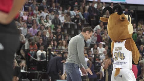 Slow-motion-shot-of-a-mascot-playing-basketball-in-a-stadium-before-a-game