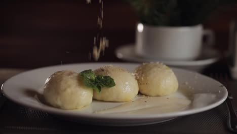 Chef-Espolvoreando-Nueces-Sobre-Un-Delicioso-Plato-Tradicional-Ucraniano,-Albóndigas-De-Queso-Gombovtsi-En-La-Mesa-Del-Café