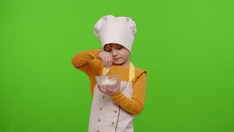 Child-girl-kid-dressed-in-apron-and-hat-like-chef-cook-stir-flour-in-plate-on-chroma-key-background