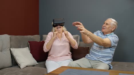 Ältere-Frau-Spielt-Spiel-In-Virtual-Reality-Headset-Brille,-Mann-Lacht-über-Ihre-Aktion-Zu-Hause