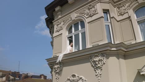 Bride-in-boudoir-dress-sitting-on-window-sill-wedding-morning-preparations-woman-in-night-gown,-veil