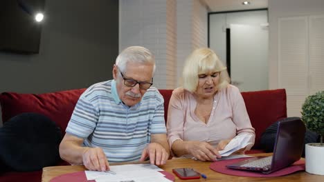 Senior-couple-checking-papers,-domestic-bills,-planning-budget-investment-loan-insurance-payment