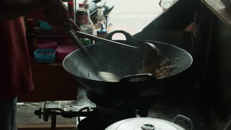 Hands-of-a-man-are-cooking-rice-and-vegetables-for-Nasi-Goreng-in-an-indonesian-kitchen-in-a-restaurant,-static-shot