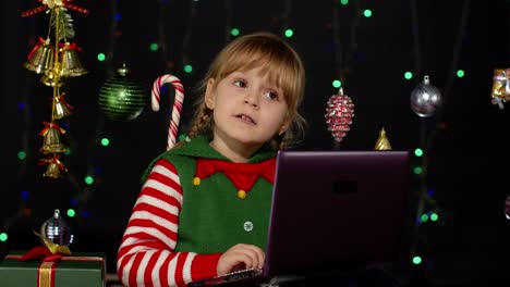 Niña-Vestida-De-Elfo-Navideño-Haciendo-Compras-En-Línea-Usando-Una-Computadora-Portátil,-Navegando-En-Las-Redes-Sociales