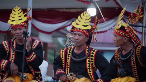 Three-asian-men-are-singing-with-traditional-costumes-on-at-the-Nias-Pro-Competition-in-Indonesia,-close-up,-windy-day,-colorful-costumes