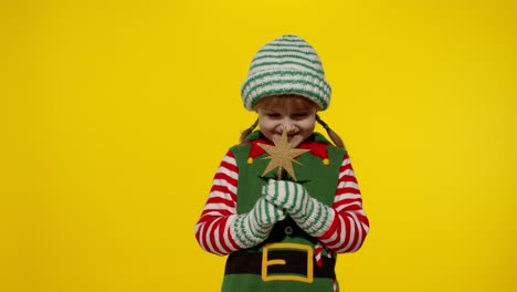 Kid-girl-in-Christmas-elf-Santa-helper-costume-holding-star-toy-and-making-a-wish.-New-Year-holiday