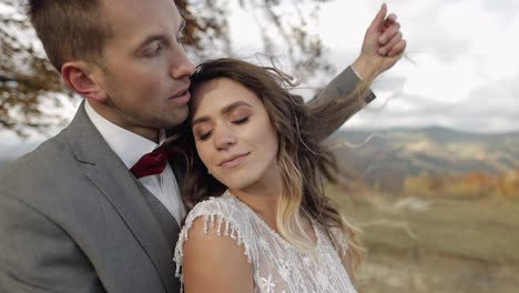 Lovely-young-newlyweds-bride-and-groom-embracing,-hugging-on-mountain-slope,-wedding-couple-in-love