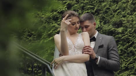 Newlyweds,-caucasian-groom-with-bride-stay-on-stairs-in-park,-wedding-couple,-man-and-woman-in-love