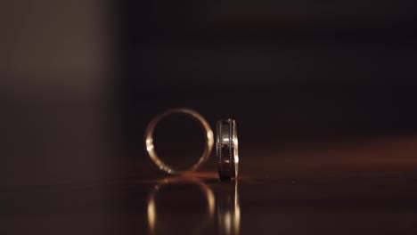 Close-up-of-turning-spinning-rotating-wedding-rings-of-groom-and-bride-on-table,-marriage-symbols