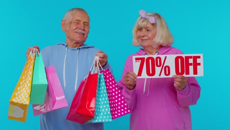 Senior-grandparents-showing-shopping-bags-and-Up-To-70-Percent-Off-banner-text,-Black-Friday-holiday