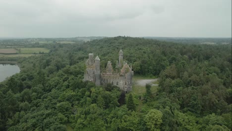 Dromore-castle-surrounded-by-lush-green-forest-in-county-limerick-ireland,-aerial-view