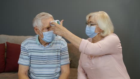 Pareja-De-Ancianos-Mide-La-Temperatura-Con-Un-Termómetro-Digital-Sin-Contacto-Durante-El-Bloqueo-Del-Coronavirus