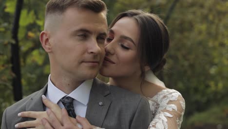 Lovely-newlyweds-caucasian-bride-embracing-groom-in-park-making-kiss,-wedding-couple-family-hugging