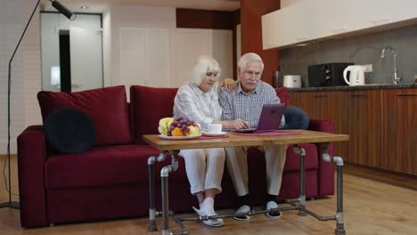 Senior-old-couple-grandparents-talking-and-using-digital-laptop-computer-at-home.-Internet-shopping