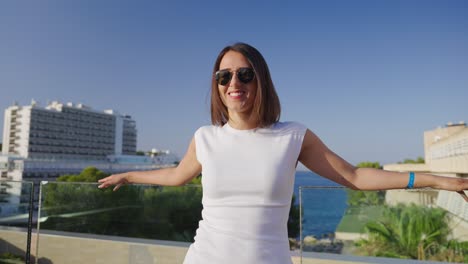 Pretty-female-lean-on-balcony-glass-safety-barrier,-summertime-in-Mallorca