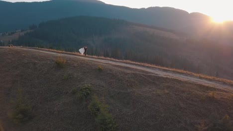 Newlyweds-dancing-on-a-high-slope-of-the-mountain.-Groom-and-bride.-Aerial-view