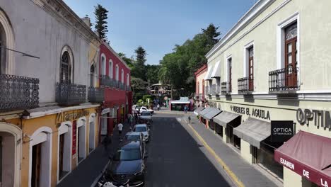 Vuelo-En-Reversa-Sobre-Calle-Libertad-Descubre-Casas-De-Colores,-El-Parque-De-La-Ciudad-Y-A-Lo-Lejos-El-Zócalo-De-Atlixco