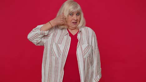 Cheerful-senior-woman-in-shirt-looking-at-camera-doing-phone-gesture-like-says-hey-you-call-me-back