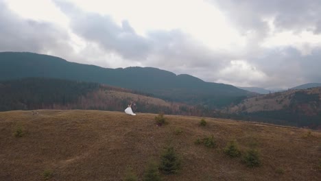 Lovely-newlyweds-bride-groom-dancing-on-mountain-autumn-slope,-aerial-view,-wedding-couple-family