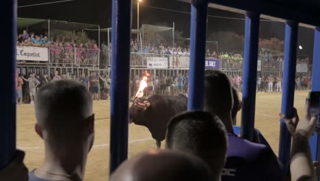 Vista-Desde-Detrás-De-Un-Cadafal-De-Un-Toro-Con-Bolas-De-Fuego-En-Sus-Cuernos-En-Una-Plaza-De-Toros-Con-Espectadores-En-Un-Evento-De-Toro-Embolado-En-Sagunto