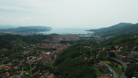 Foce-la-spezia,-italy-showing-the-town,-green-hills,-and-coastline-in-the-distance,-aerial-view