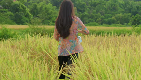 Mujer-Agricultora-Sembrando-Semillas-En-Una-Plantación-De-Arroz-En-Asia,-Vistiendo-Ropa-Tradicional,-Vista-Frontal-Y-Posterior