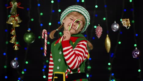 Niña-En-Traje-De-Ayudante-De-Papá-Noel-Elfo-De-Navidad-Con-Paleta-De-Bastón-De-Caramelo-Sonriendo-Alegremente