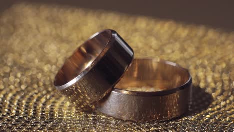 Wedding-gold-rings-lying-on-shiny-glossy-surface.-Shining-with-light.-Close-up