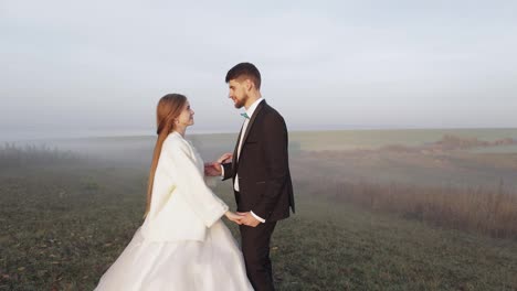 Newlyweds.-Caucasian-groom-with-bride-on-the-morning-field.-Fog.-Wedding-couple