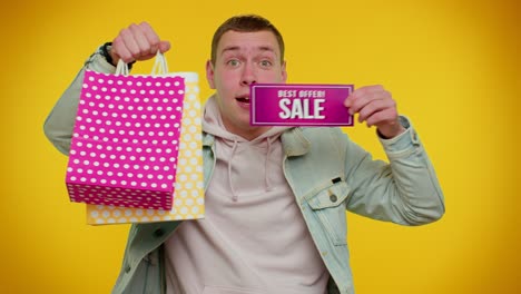 Happy-student-man-showing-Sale-inscription-banner-text,-advertising-discounts-low-holidays-prices