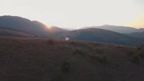 Newlyweds-running-on-a-high-slope-of-the-mountain.-Groom-and-bride.-Aerial-view