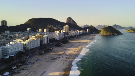 Drone-approaching-people-on-the-Copacabana-Beach,-sunny-evening-in-Rio-de-Janeiro