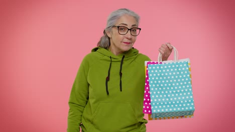 Abuela-Mayor-Mostrando-Bolsas-De-Compras-Y-Hasta-Un-40-Por-Ciento-De-Descuento-En-Pancartas-De-Inscripciones,-Viernes-Negro