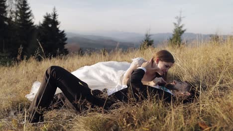 Newlyweds.-Caucasian-groom-with-bride-lie-on-the-grass-on-mountain-slope