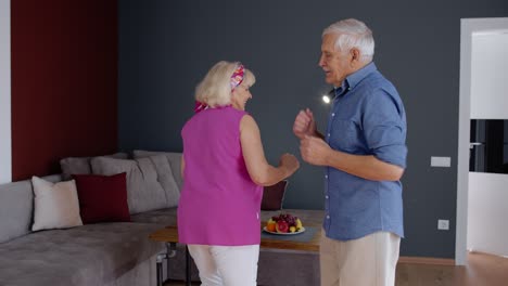 Senior-mature-couple-dancing-together-in-room-at-home-during-quarantine-lockdown-for-coronavirus