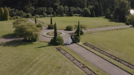 Recién-Casados,-Novio-Caucásico-Con-Novia-Caminando,-Tomados-De-La-Mano-En-El-Parque,-Pareja-De-Novios,-Vista-Aérea