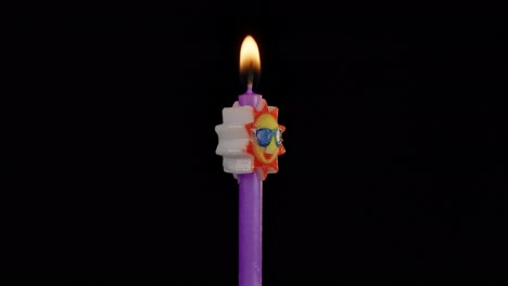 Birthday-festive-candle-in-form-of-sun-in-sunglasses-turning,-spinning-isolated-on-black-background