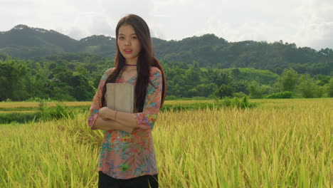 Joven-Ingeniera-Agricultora-Sosteniendo-Una-Tableta-5g-Portátil-De-Pie-En-Una-Plantación-De-Arroz,-Retrato-En-Cámara-Lenta