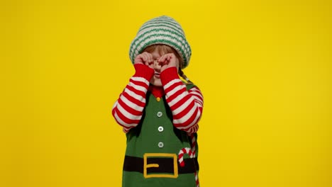 Kid-girl-in-Christmas-elf-Santa-helper-costume-crying-and-wipes-tears.-New-Year-holiday-celebration