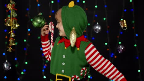 Kid-girl-in-Christmas-elf-Santa-helper-costume-dancing,-fooling-around.-New-Year-holiday-celebration