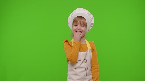 Child-girl-dressed-in-apron-like-chef-cook-eats-delicious-fresh-strawberries-and-laughing-out-loud